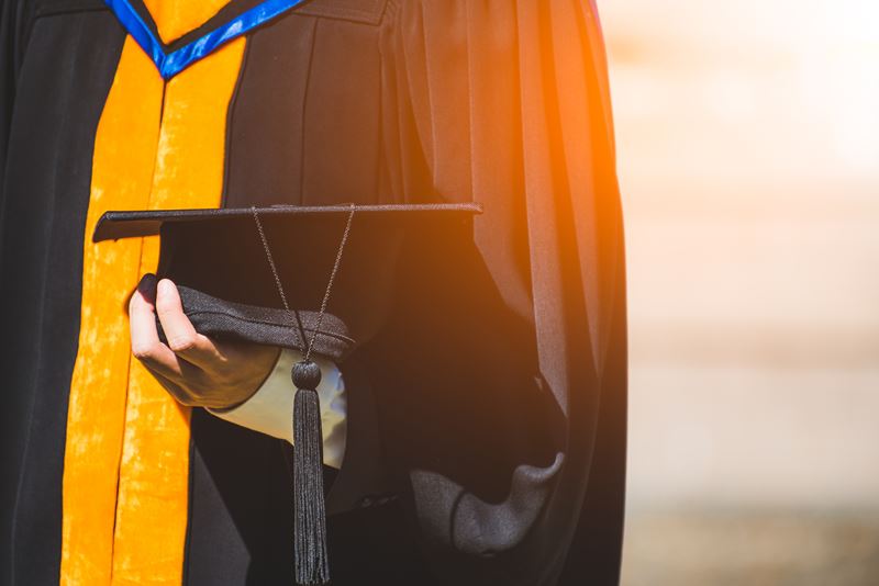 Close up of a graduate holding their graduation cap